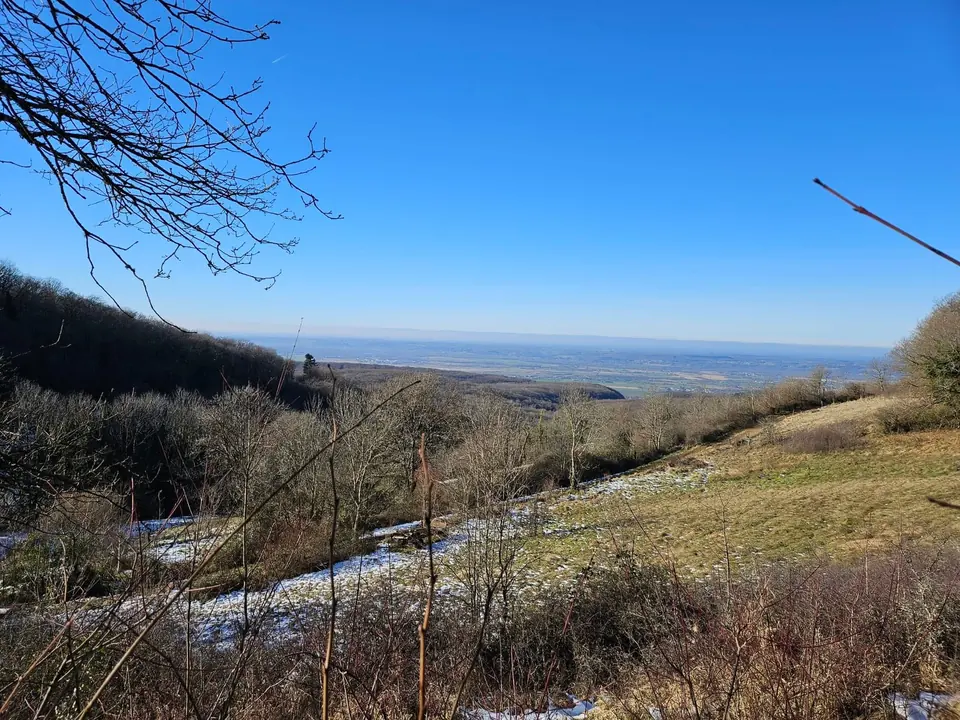 Une prairie saupoudrée de neige, face à la plaine