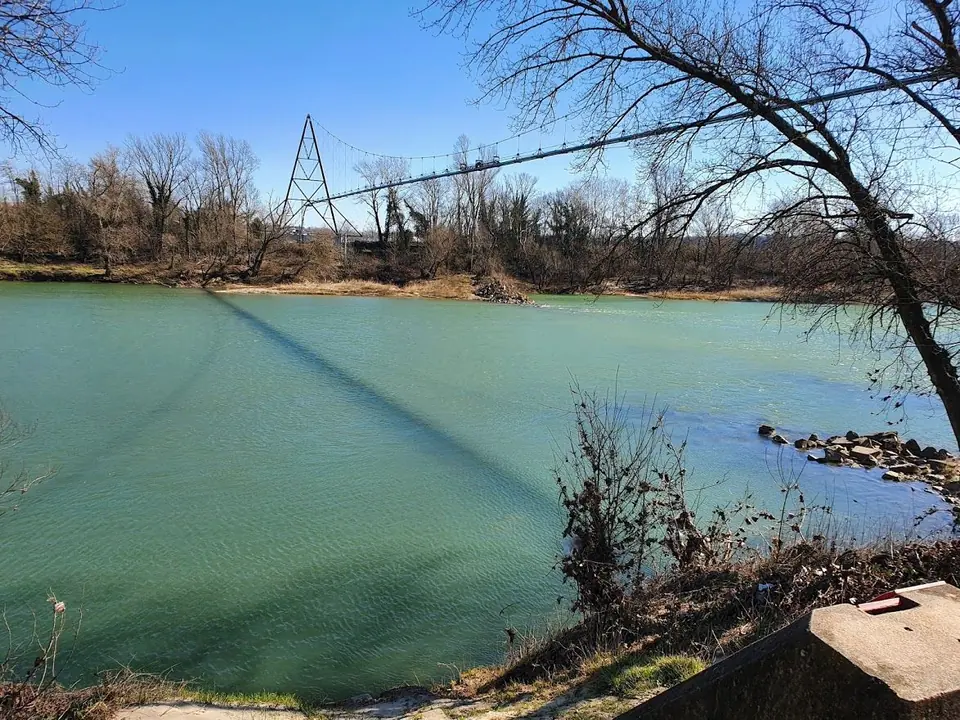 Une passerelle suspendue enjambe les eaux vertes du Rhône en hiver